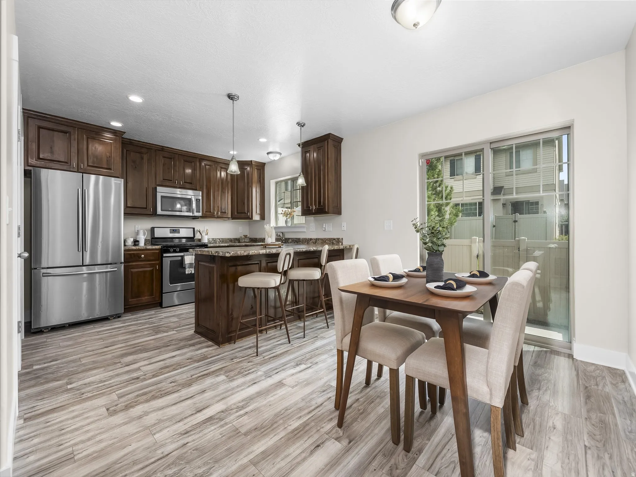 Wood-finish flooring throughout, dark wood cabinetry, stainless steel appliances, and a sliding glass door