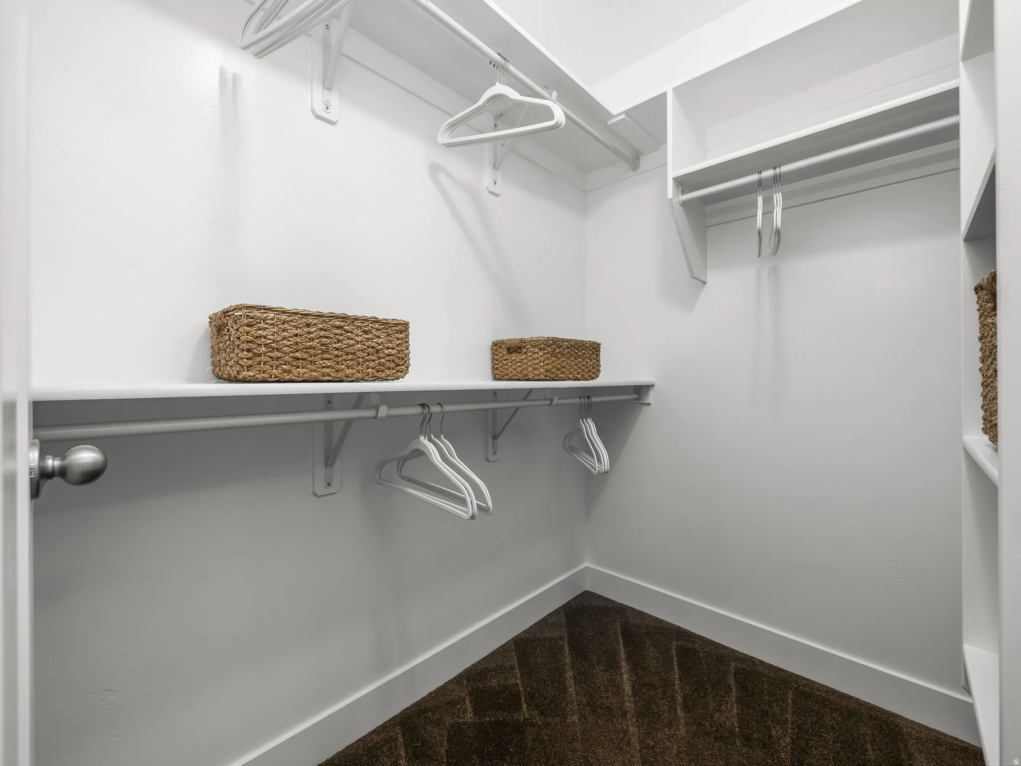 White walls with built-in shelving, hanging rods, and dark brown chevron patterned carpeting