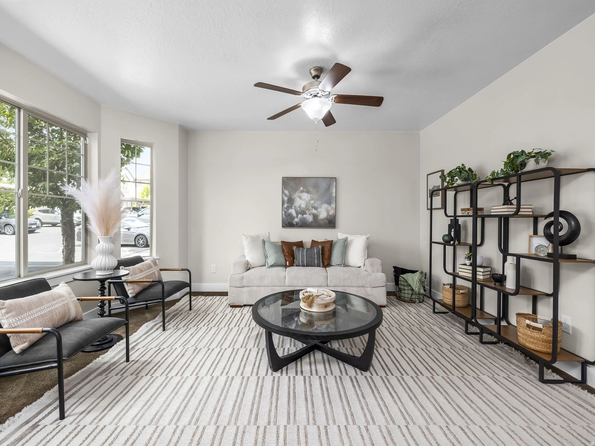 Spacious living area featuring large windows, a ceiling fan, and a built-in shelving unit