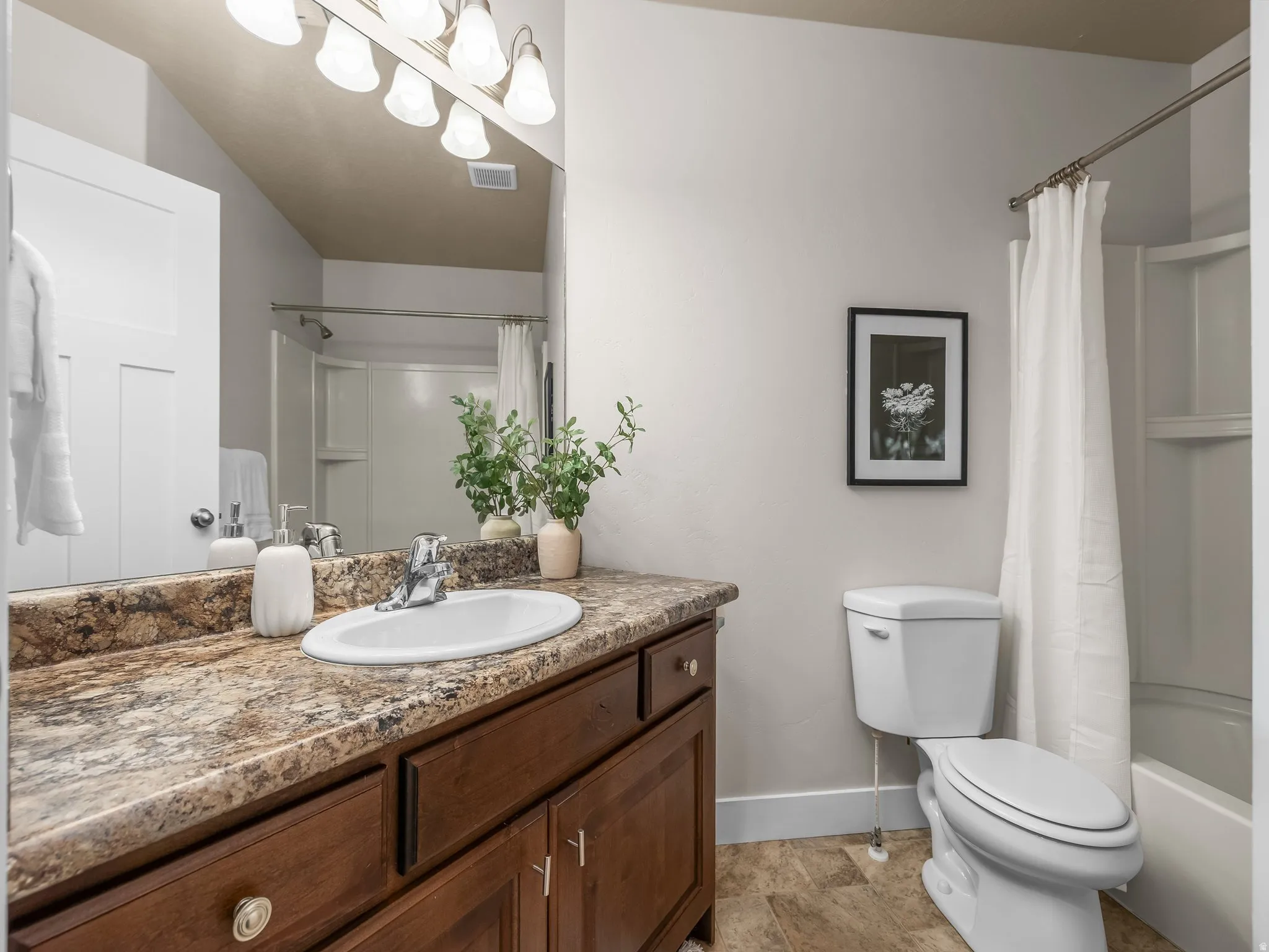 Vanity with wood-finish cabinetry, a large basin sink, and a multi-light fixture