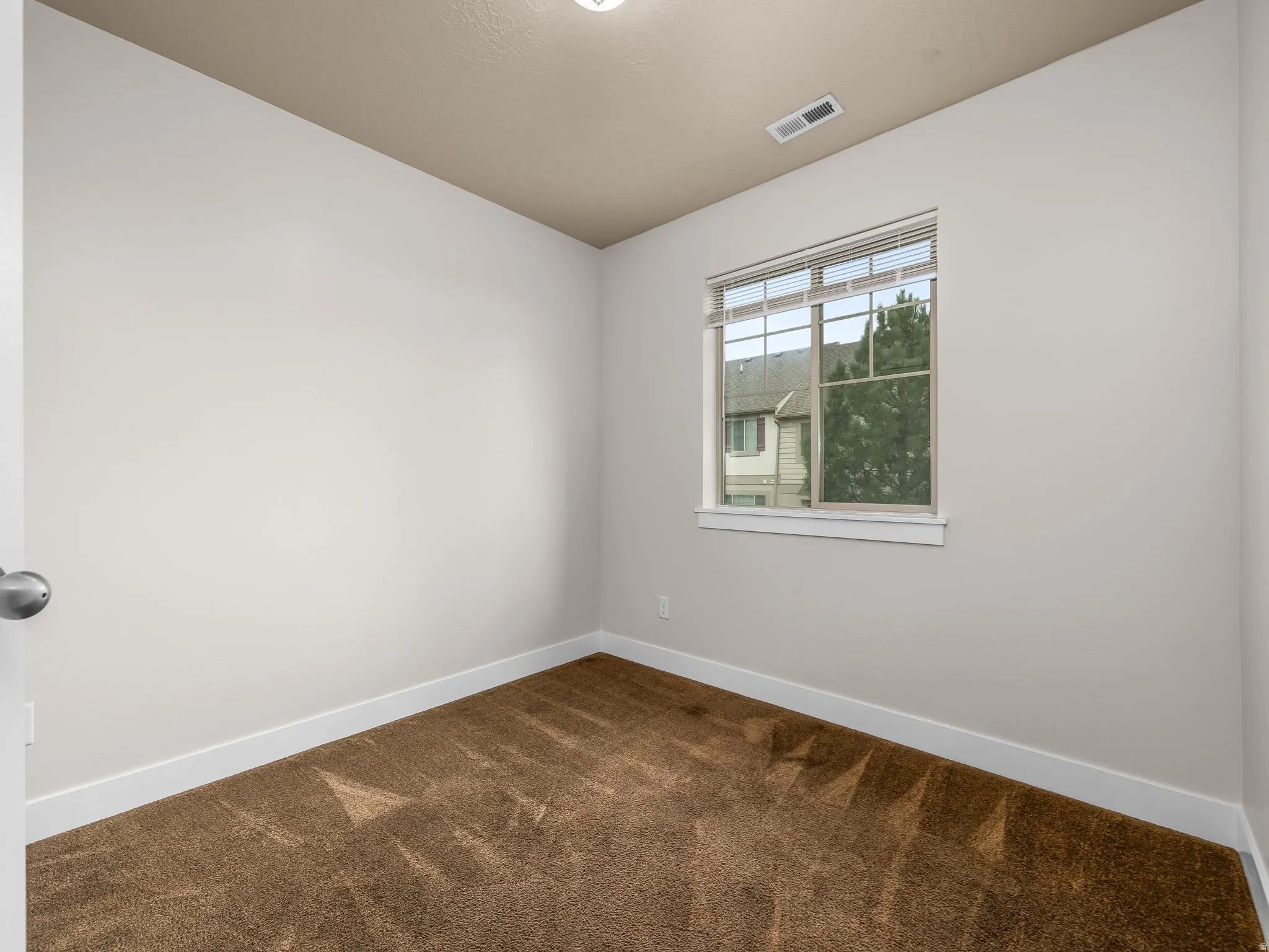 Neutral wall finishes, textured carpeting, and a multi-pane window
