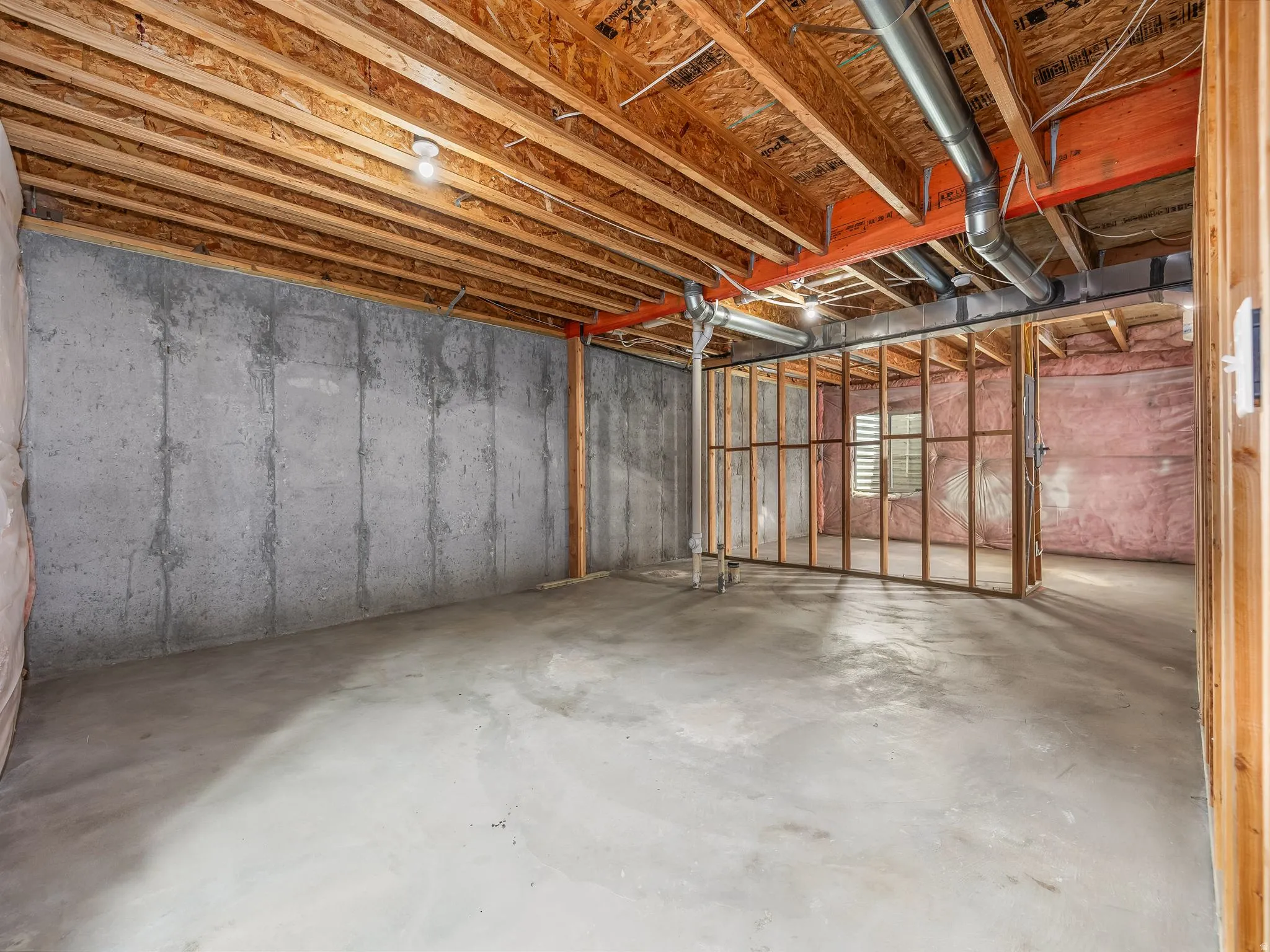 Unfinished basement featuring concrete walls and flooring, exposed ceiling joists, and structural framing