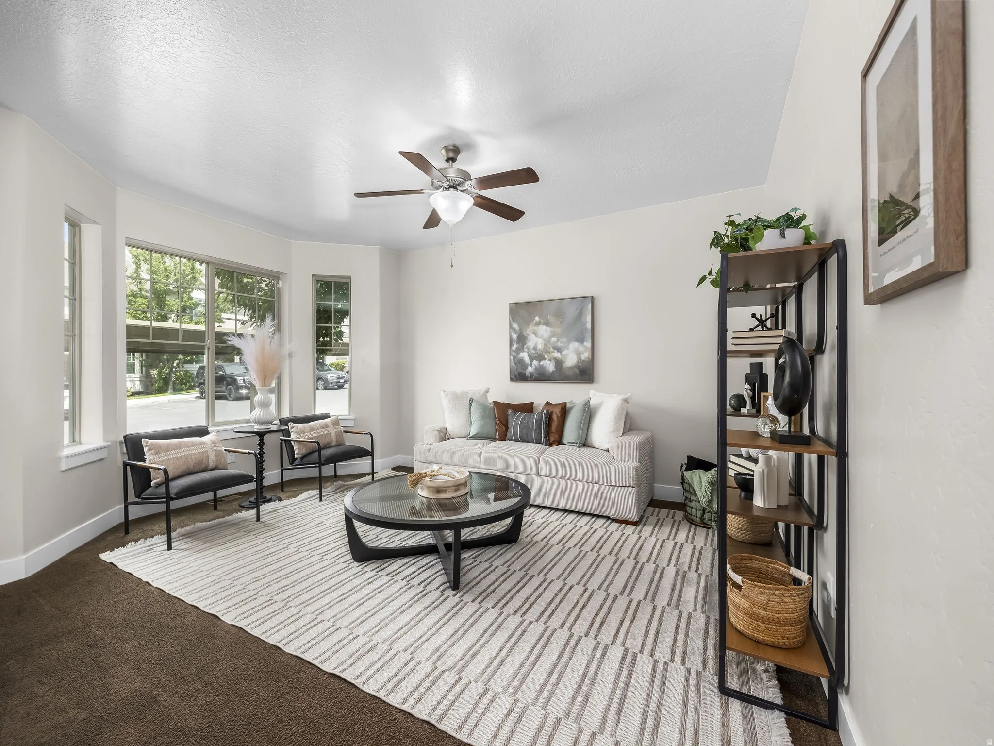 Spacious room with a ceiling fan, bay windows, and carpeted flooring