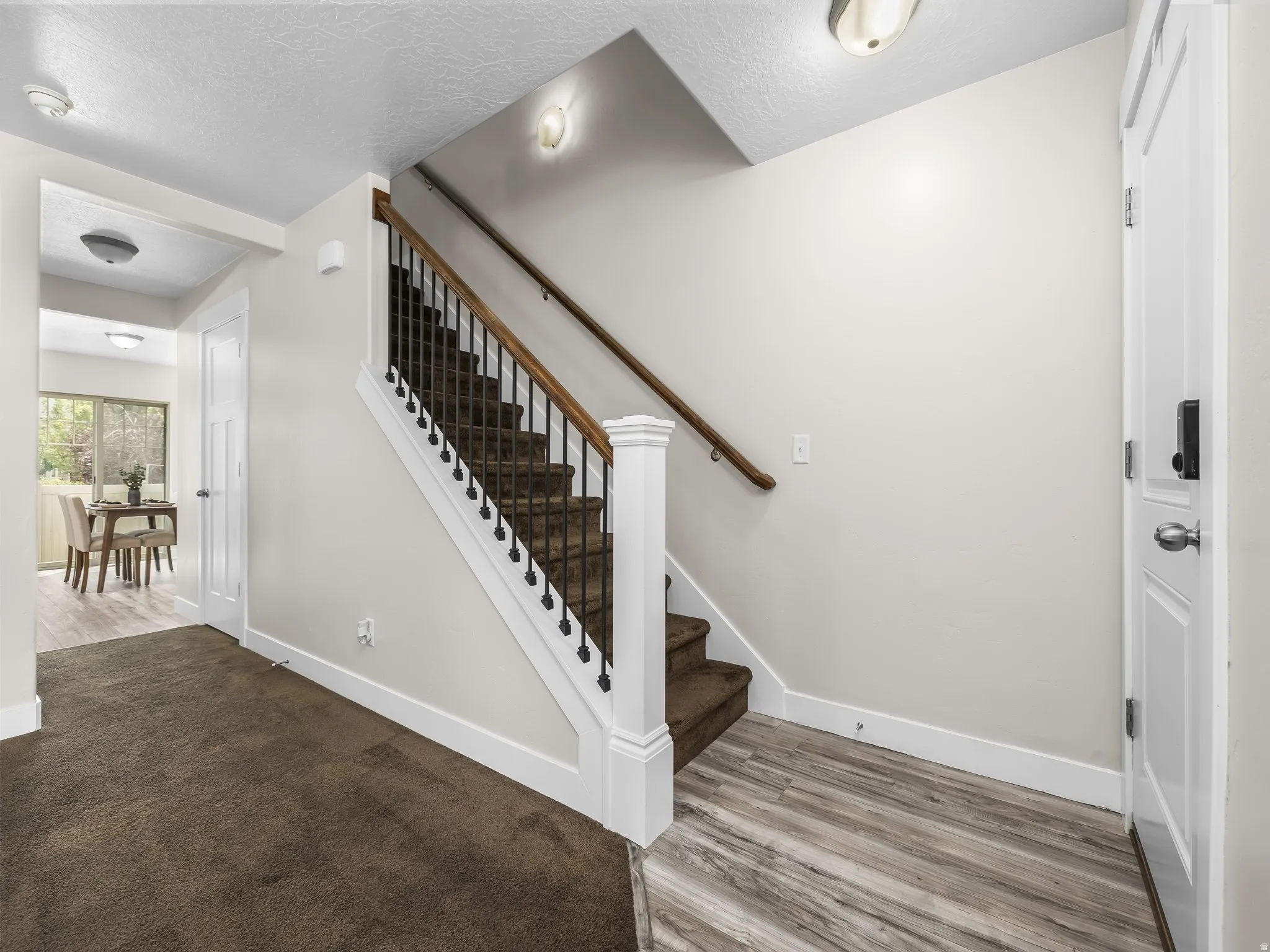 Entry foyer with wood-finish flooring transitioning to plush carpeting