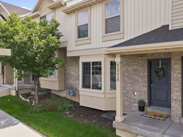 Brick and siding exterior with a dark gray entry door, concrete steps, and a bay window
