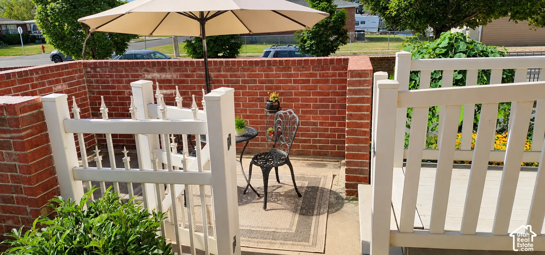 Enclosed patio area featuring a brick privacy wall, white picket gate, and concrete flooring
