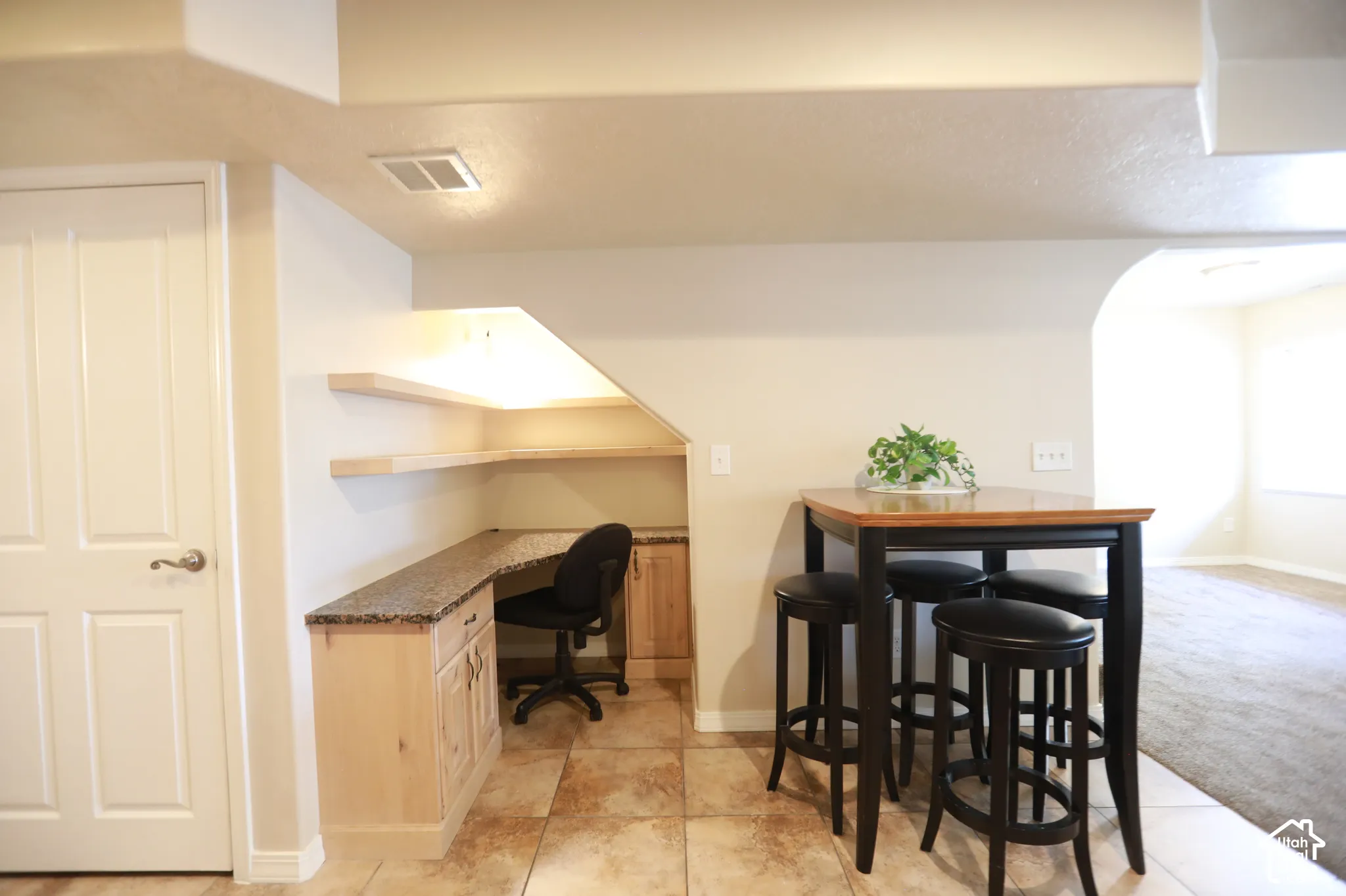 Built-in desk area with wood cabinetry, stone-finish countertop, and floating shelves