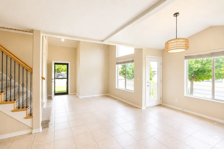 Ceramic tile flooring, vaulted ceilings, and large windows with blinds