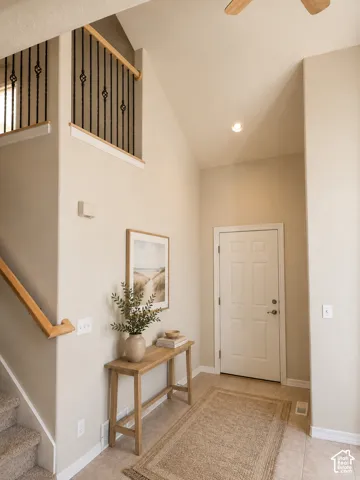 Vaulted ceiling foyer featuring a paneled entry door, recessed lighting, and tile flooring