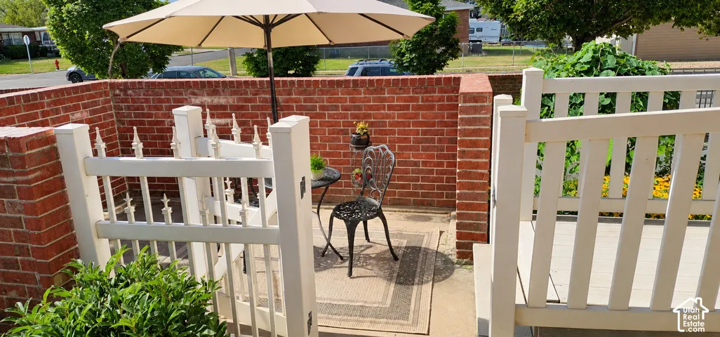 Enclosed patio area featuring a brick privacy wall, white picket gate, and concrete flooring