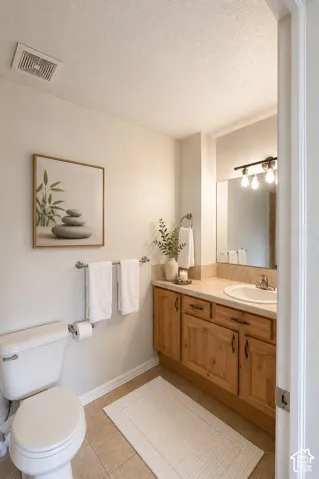 Spa-inspired bathroom featuring warm wood cabinetry with ample storage, ceramic tile flooring, and a framed mirror with integrated vanity lighting