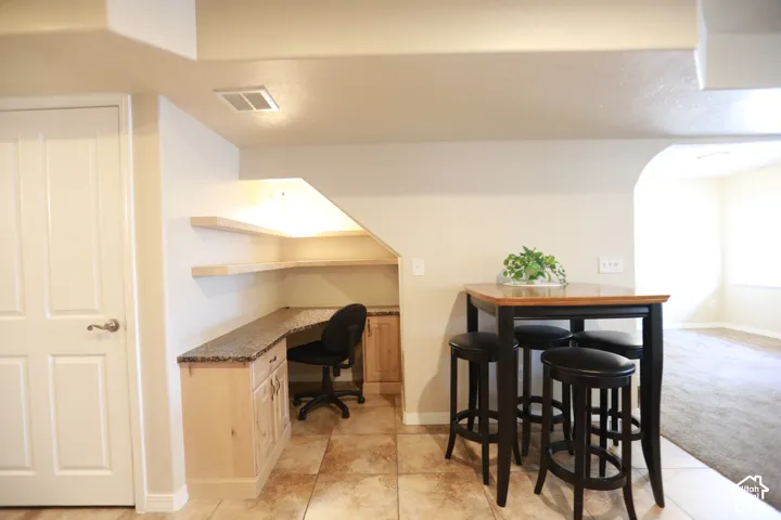 Built-in desk area with wood cabinetry, stone-finish countertop, and floating shelves