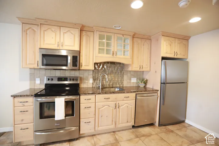 Kitchen featuring wood cabinetry, stainless steel appliances, granite-look countertops, tile backsplash, and recessed lighting