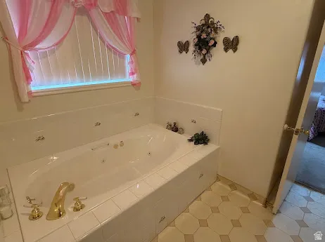White jetted tub with gold-tone fixtures, surrounded by white ceramic tile