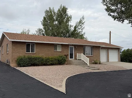 Brick exterior with a brown shingle roof, white trim windows, a two-car garage, and a paved driveway