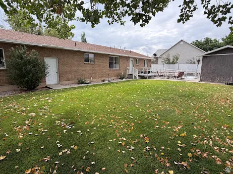 Brick exterior with a white deck, green lawn, and a storage shed