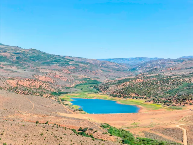 Expansive mountainous landscape featuring a large body of water, distant hills, and varied terrain