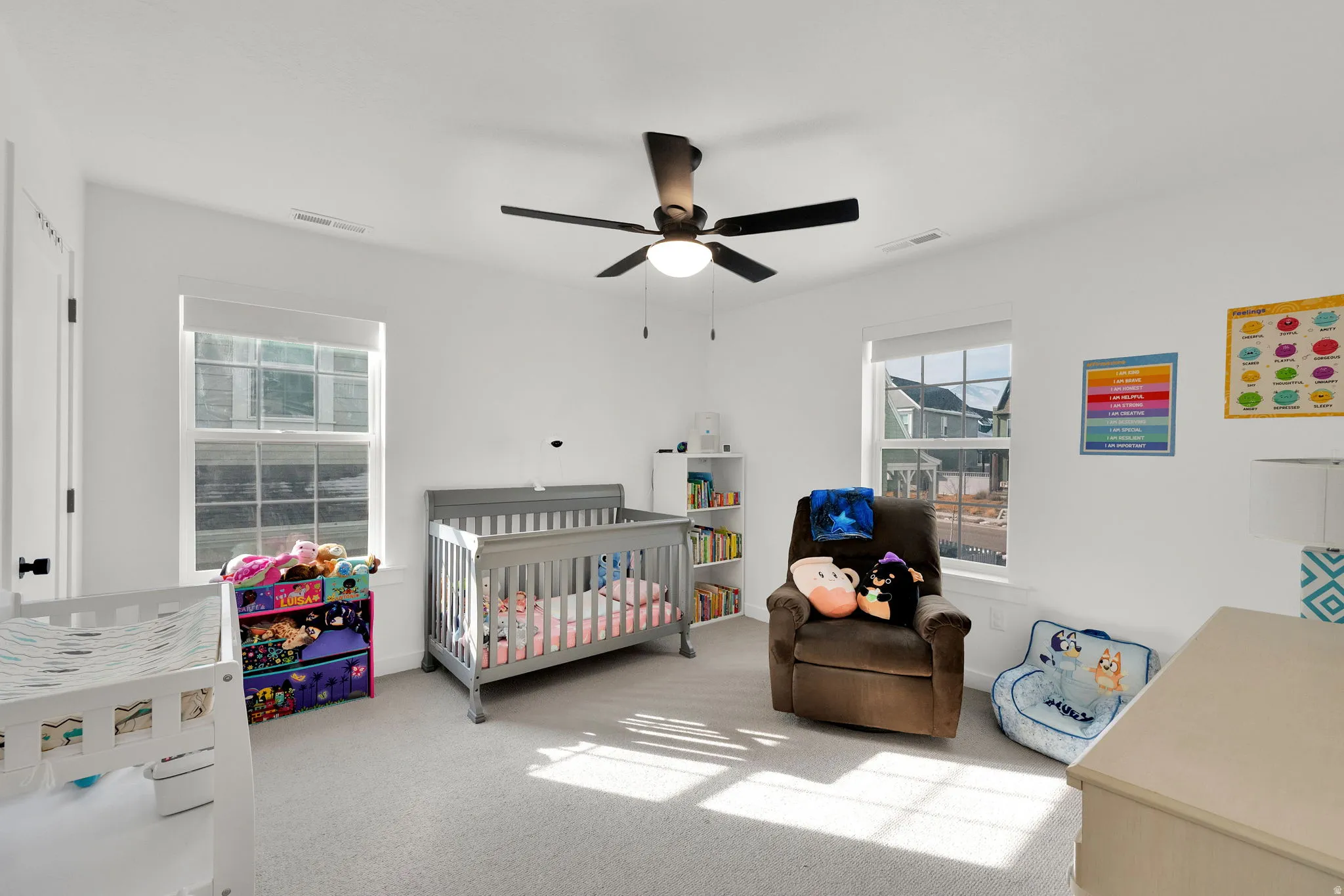Recessed lighting, ceiling fan with integrated light, two windows with window treatments, and neutral carpeting
