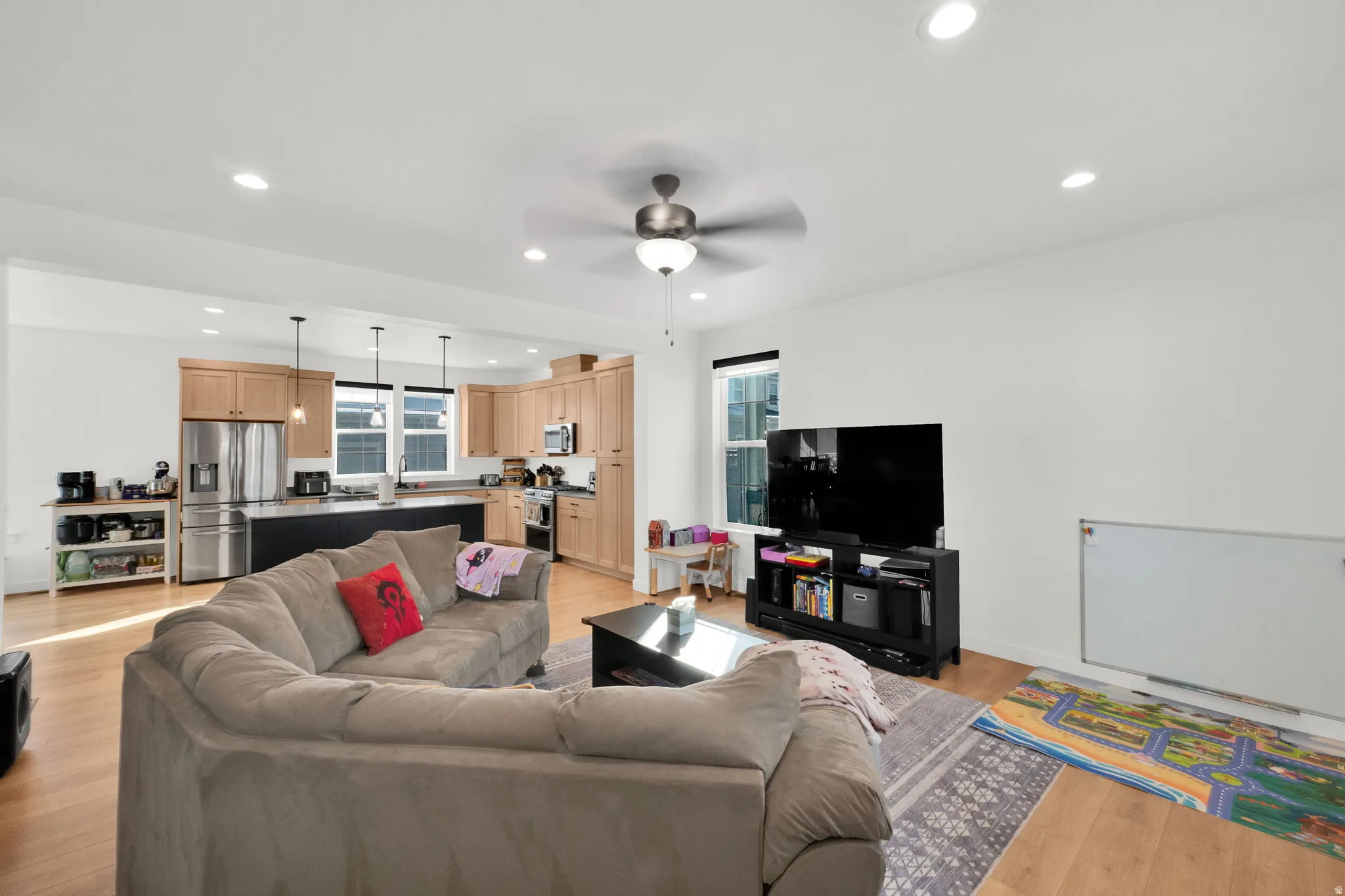 Open-concept living space featuring wood-finish flooring, recessed lighting, and a ceiling fan