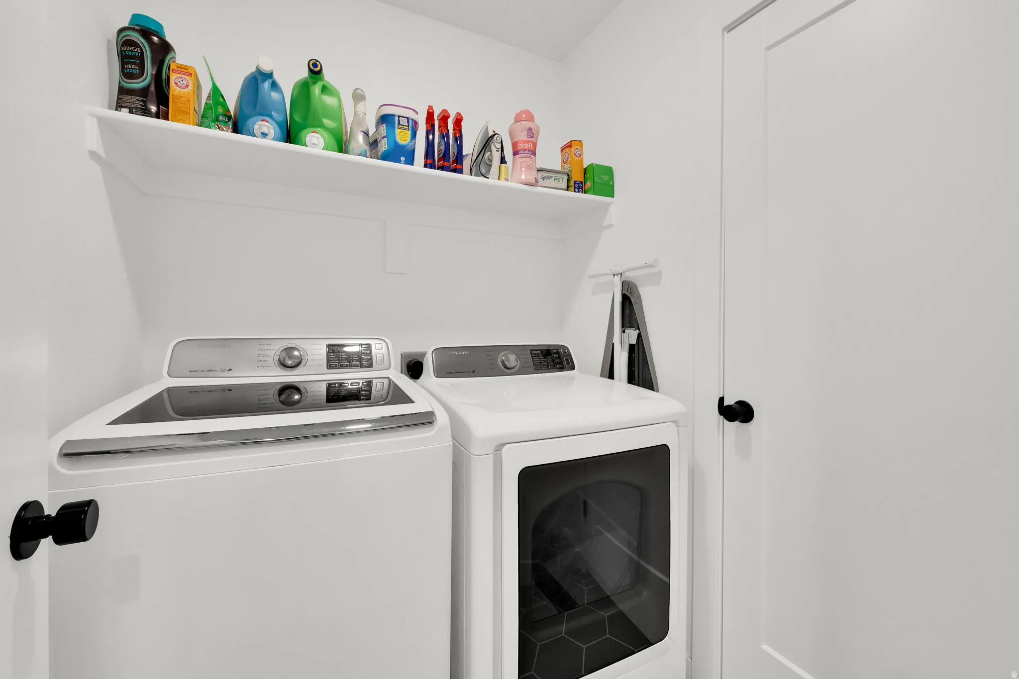 Laundry area featuring a built-in shelf, white walls, and a white door with a black knob