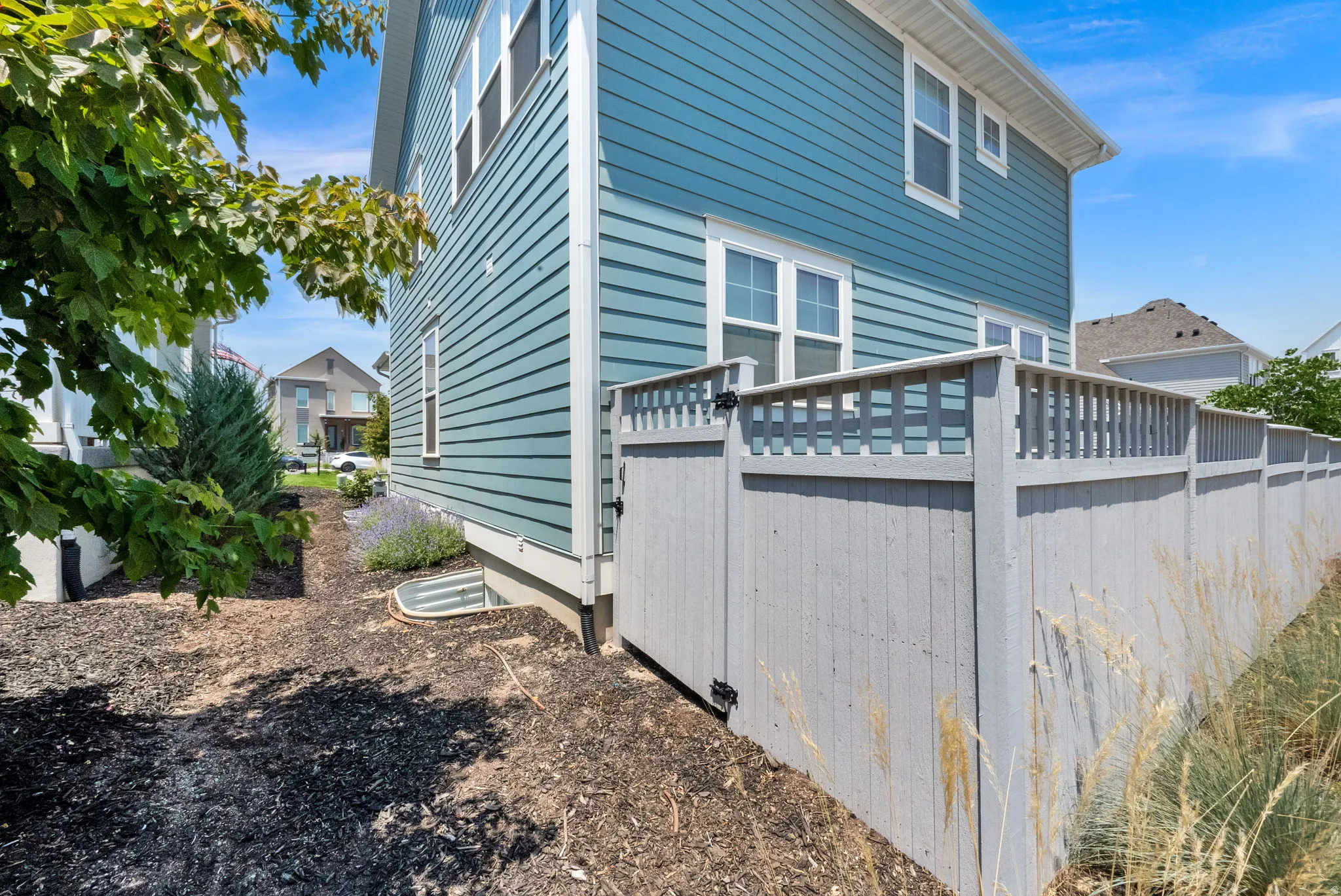 Turquoise siding exterior with white window trim and a light gray privacy fence