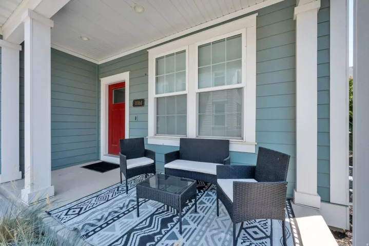 Covered front porch featuring a red entry door, horizontal siding, and multiple windows with white trim