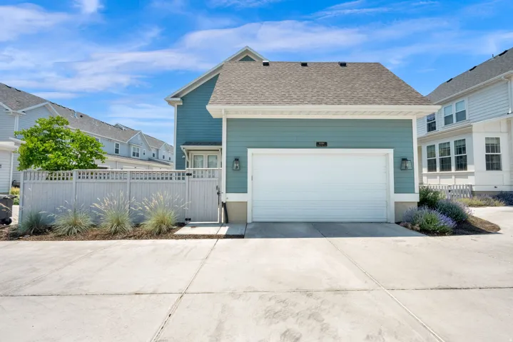 Attached two-car garage with a white door, exterior sconces, and siding in a blue-green finish