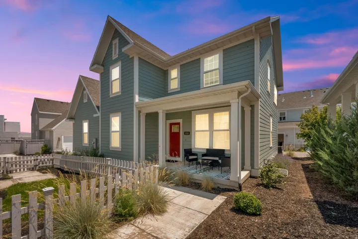 Two-story exterior with horizontal siding, covered front porch, and a red entry door