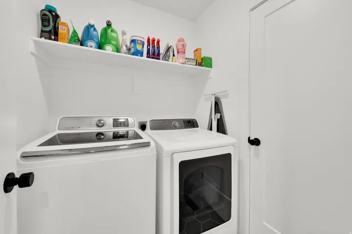 Laundry area featuring a built-in shelf, white walls, and a white door with a black knob