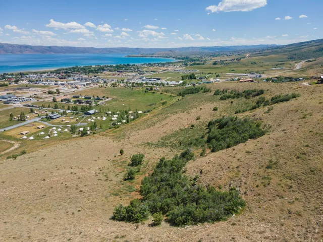 Expansive hillside lot featuring natural vegetation, distant water, and surrounding development