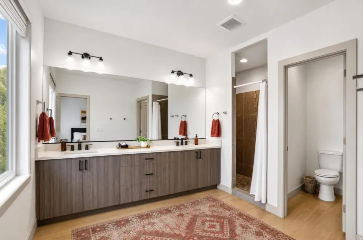 Double vanity with quartz countertop, wood-finish cabinetry, and black hardware