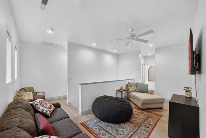 Open living area with wood-finish flooring, recessed lighting, and a ceiling fan