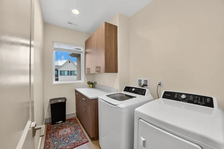 Laundry space featuring wood-finish cabinetry, white countertop, and a window