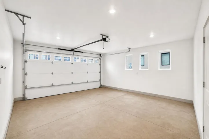 Spacious garage featuring a concrete floor, three transom windows, a panel garage door with upper window inserts, and recessed lighting