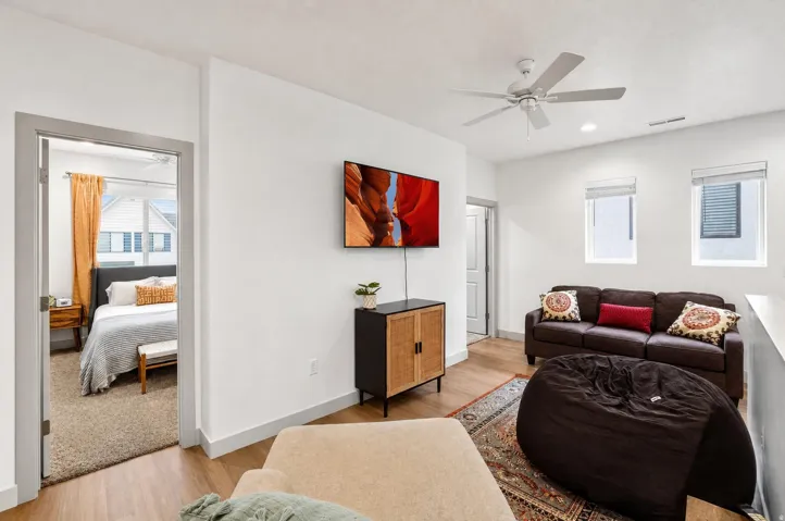 White walls, wood-finish flooring, two windows with blinds, ceiling fan, and recessed lighting