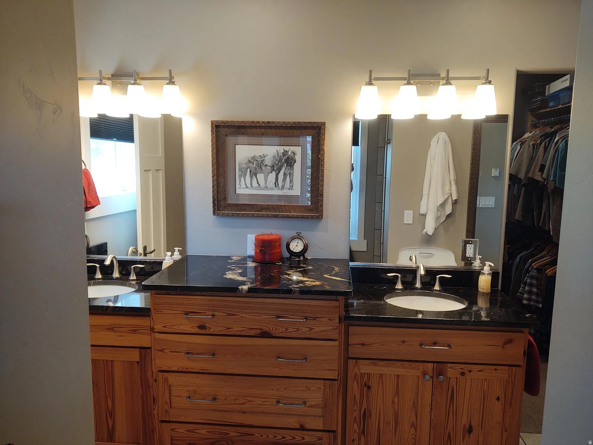 Dual vanity with wood-finish cabinetry, black countertops, and undermount sinks
