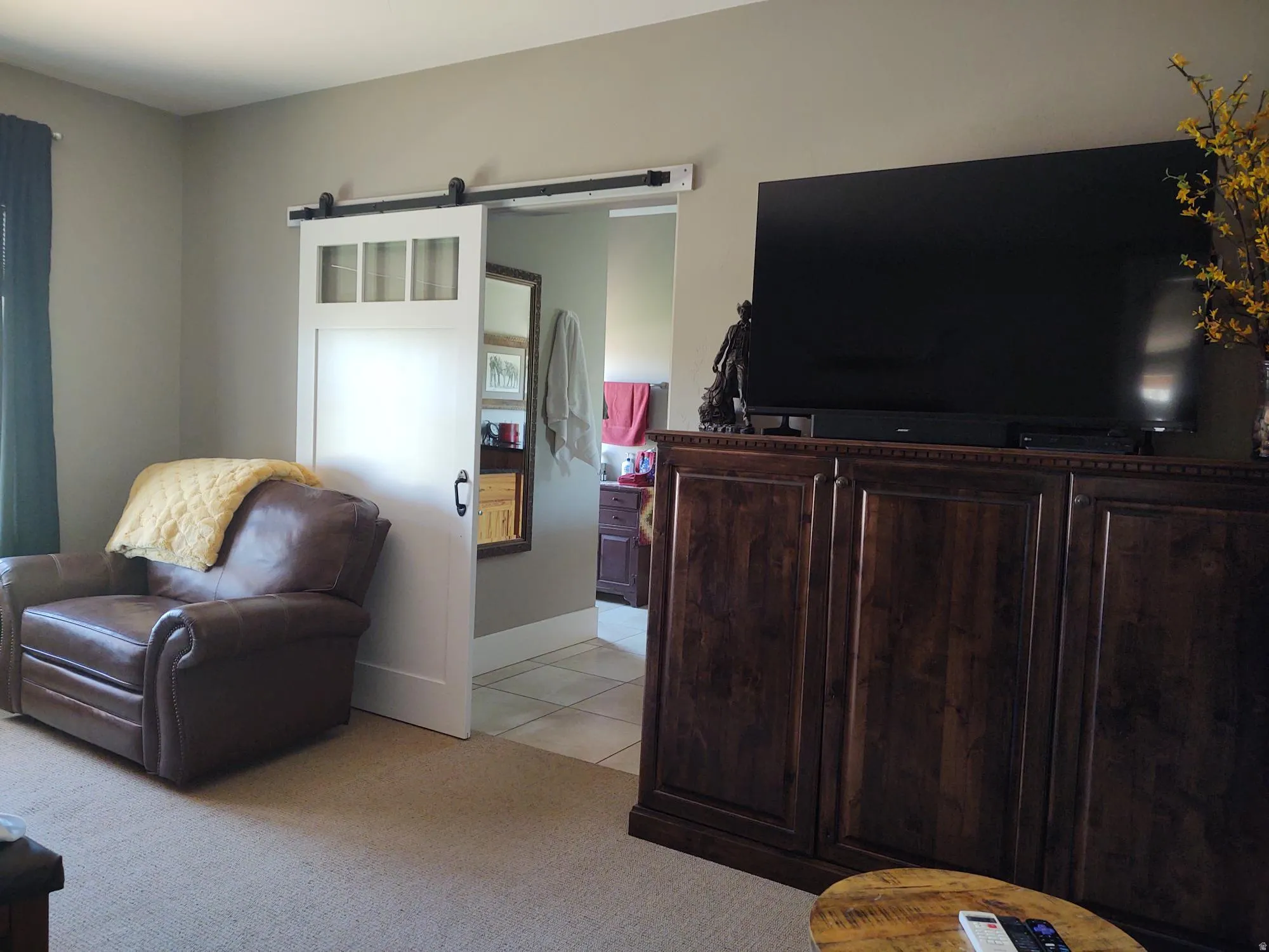 White barn door with clear glass panels, dark wood-finish media console, and neutral wall paint