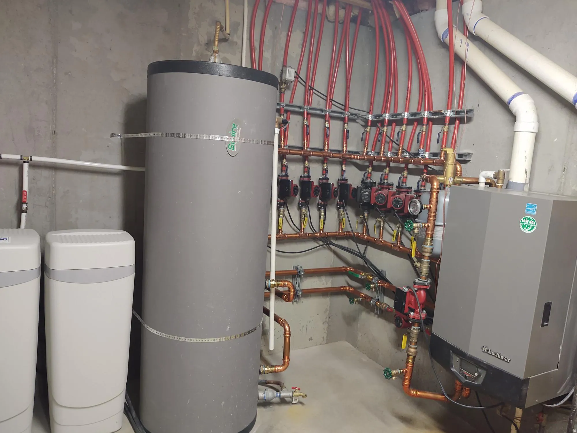 Hydronic heating system with multiple red PEX lines, copper piping, and a large water heater