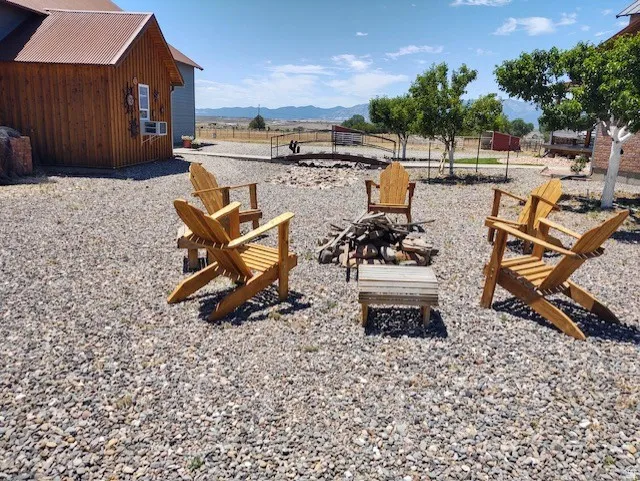 Gravel outdoor entertaining area featuring a fire pit, Adirondack chairs, and mountain scenery
