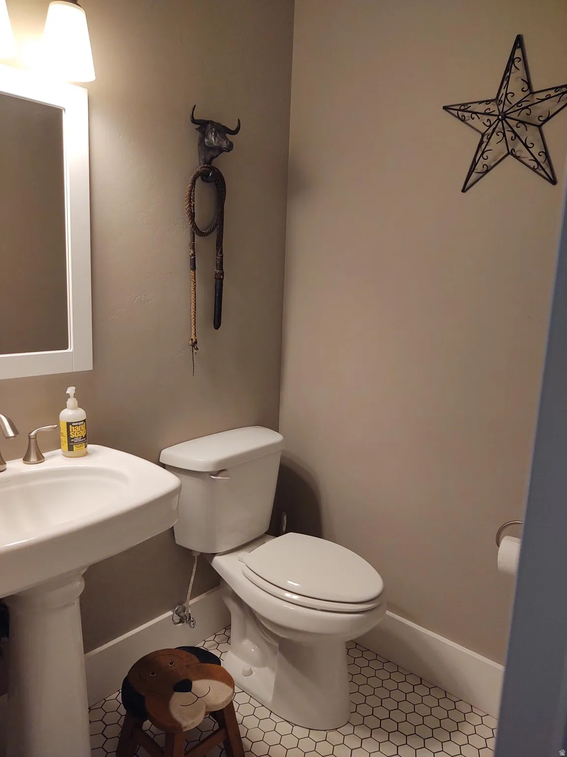 Pedestal sink with brushed nickel faucet, ceramic toilet, and hexagonal tile flooring