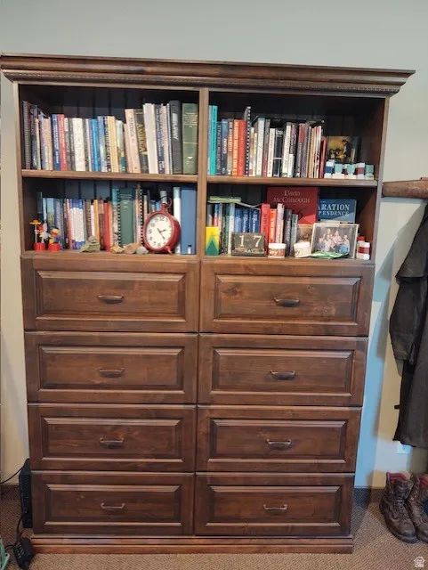 Built-in wood-finish cabinetry featuring open shelving and multiple storage drawers with dark hardware