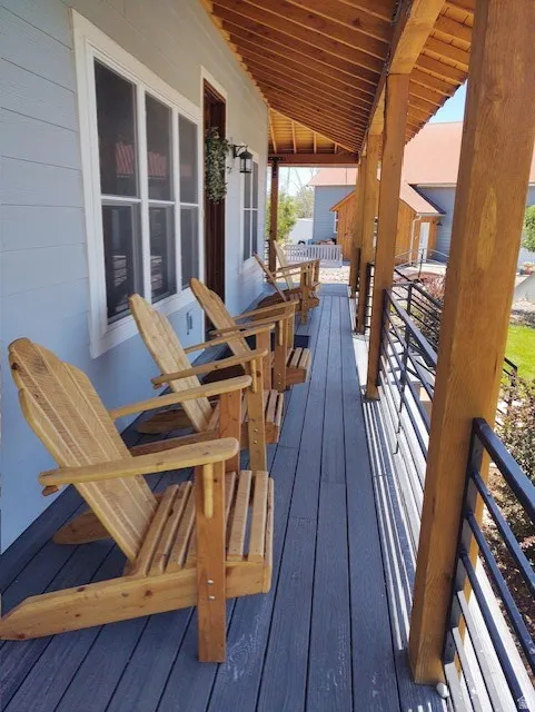 Expansive covered porch featuring a wood-plank ceiling, exposed wood beams, composite decking, and horizontal metal railings