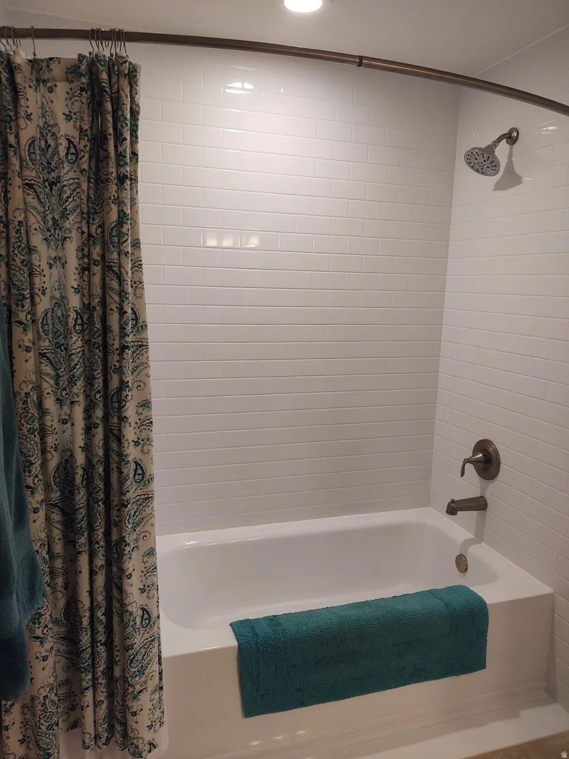 White subway tile surround, recessed lighting, and bronze-finish fixtures