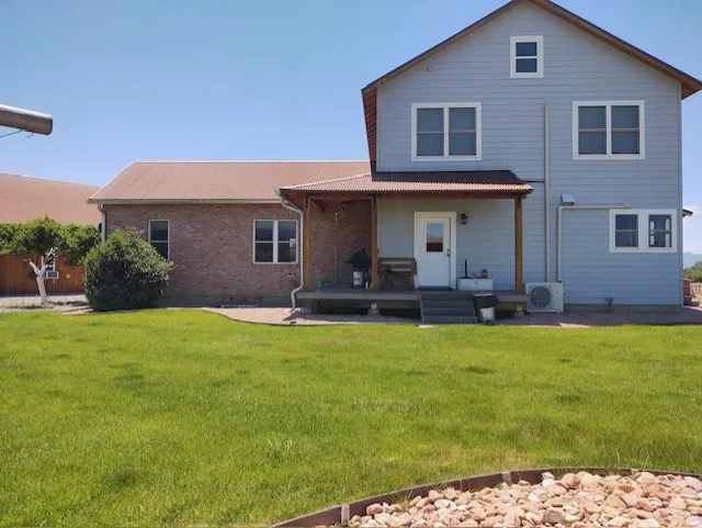 Exterior featuring a covered porch, durable metal roofing, brick and siding facade, and multiple windows
