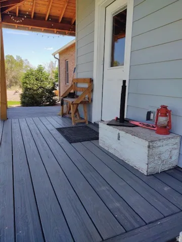 Covered porch with wood-finish decking, horizontal siding, and a wood-paneled ceiling
