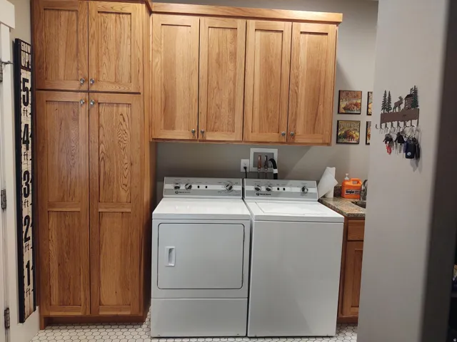 Built-in wood cabinetry, wood-finish upper cabinets, hexagon tile flooring, and integrated countertop with sink