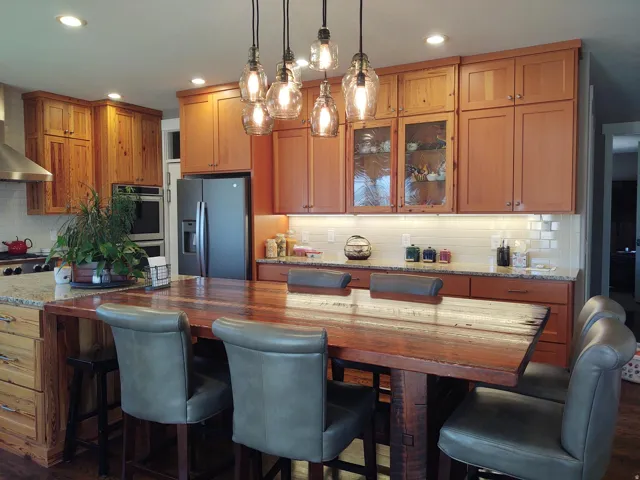 Kitchen featuring custom cabinetry, stainless steel appliances, a tile backsplash, under-cabinet lighting, and a large wood-finish island with seating