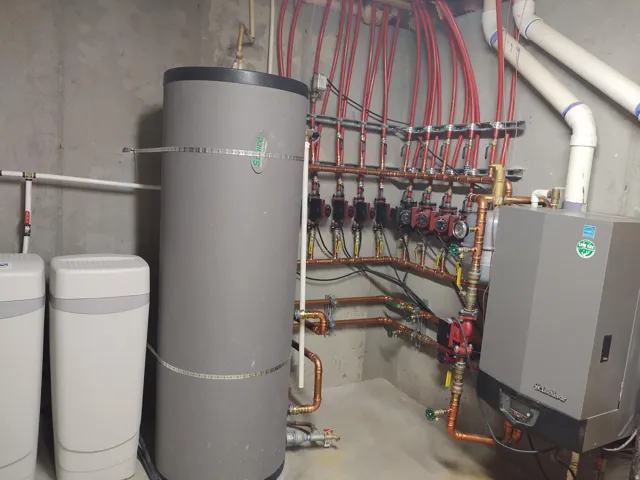 Hydronic heating system with multiple red PEX lines, copper piping, and a large water heater