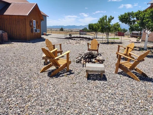 Gravel outdoor entertaining area featuring a fire pit, Adirondack chairs, and mountain scenery