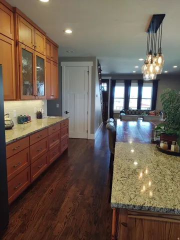 Kitchen featuring wood cabinetry, light-toned countertops, a subway tile backsplash, and dark wood-finish flooring